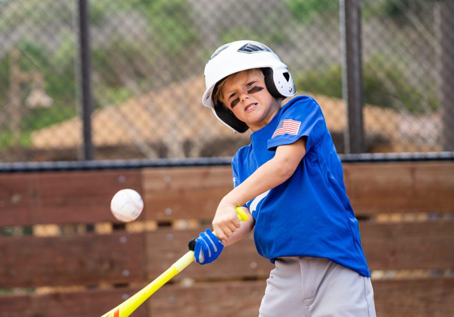 Boy swinging baseball bat at pitch.